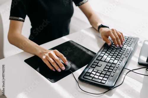 Closeup of a woman working at a computer, holding a mouse on mouse pad. photo
