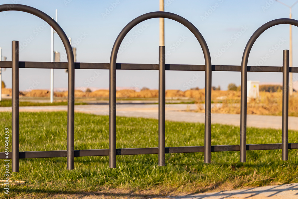 Fototapeta premium A metal fence between the roadway and the sidewalk. An empty pedestrian path with a fence. Multi-lane road with a pedestrian path next to it separated by a railing.