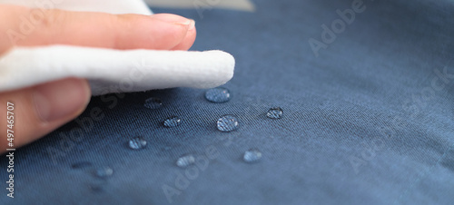 hand wipes drops of water from a cloth. Water drops on waterproof textile material. short depth of field. Waterproof fabric on sofa.