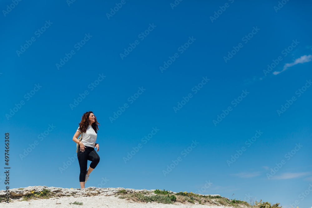 woman traveler climbs to the top of a mountain looking at the landscape