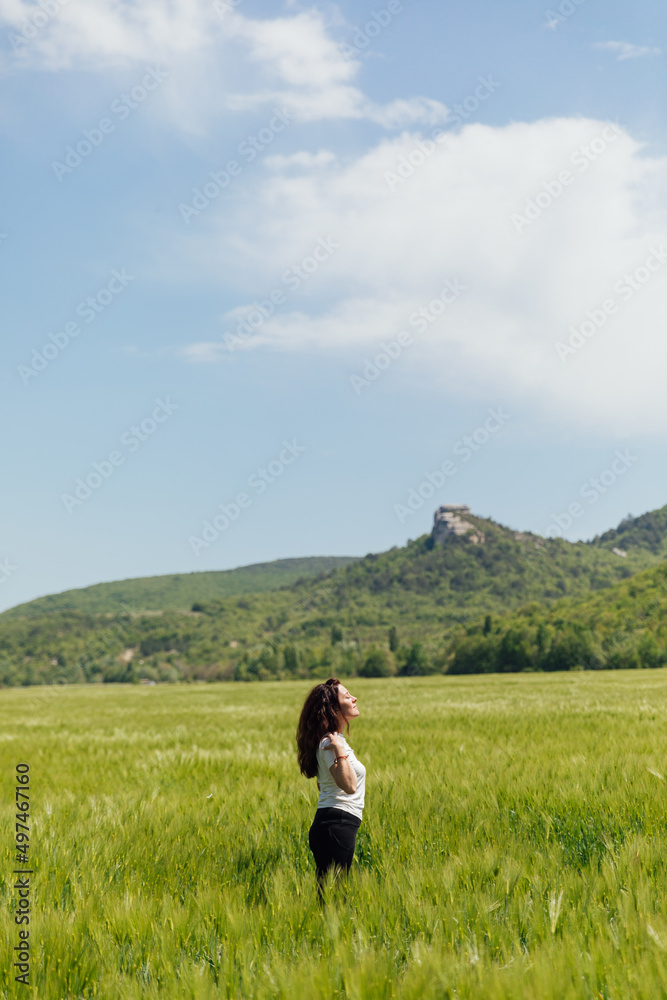 woman traveler in the field looks at the beautiful landscape