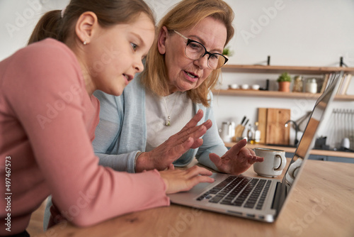 Caucasian of grandmother and her granddaughter looking on laptop at home © gpointstudio