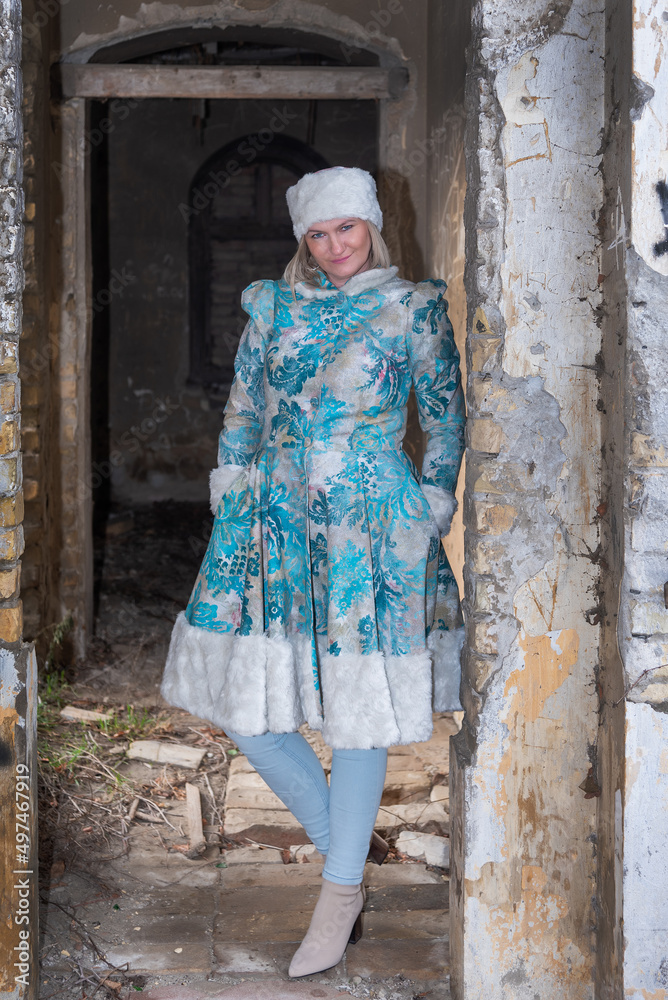 Winter queen in an abandoned castle. A beautiful woman in a winter suit
