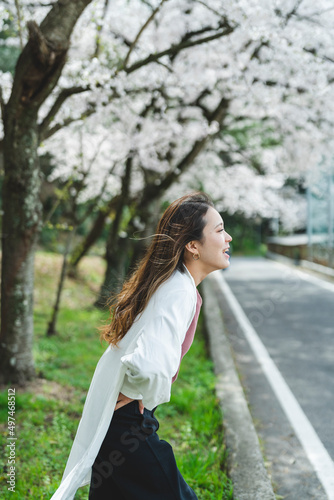 桜の花を見ながら散策する女性