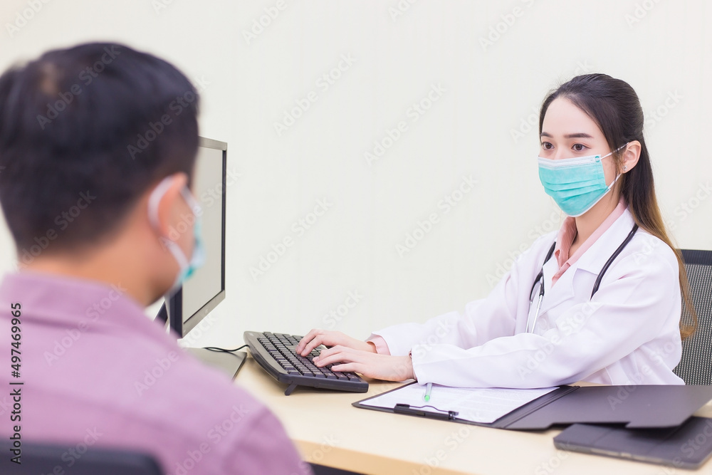 Professional Asian woman doctor records symptom of man patient in document at hospital, both of them wear medical face mask to protect Coronavirus (Covid 19) while in examination room at hospital. Professional Asian woman doctor records symptom of man patient in document at hospital, both of them wear medical face mask to protect Coronavirus (Covid 19) while in examination room at hospital.