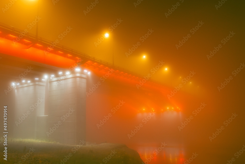 Bridge silhouette illuminated through fog at night.