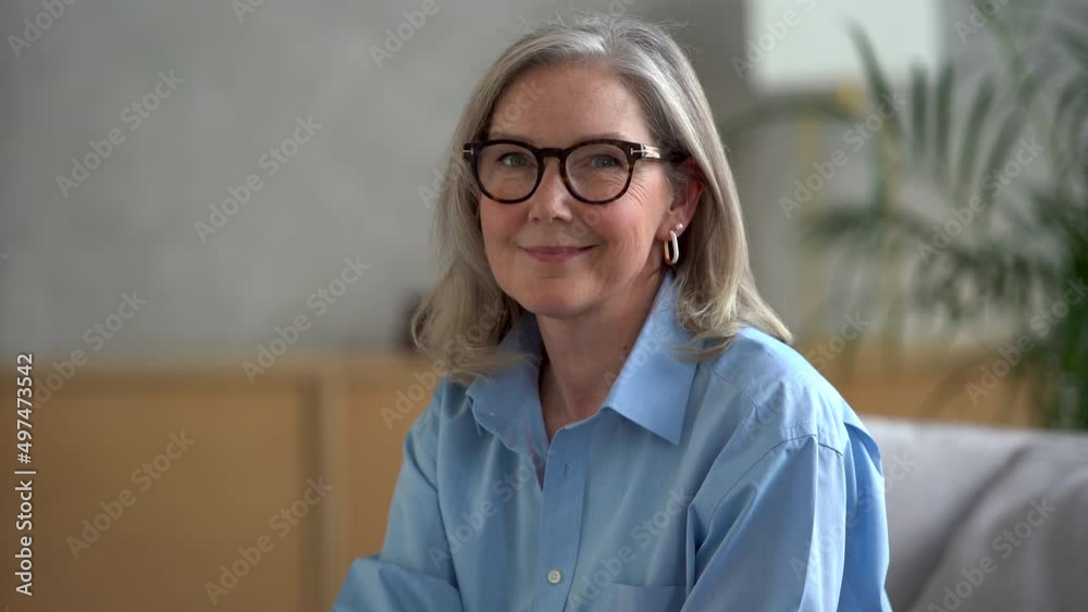 Happy mature middle aged single woman looking at camera posing at home for video portrait, smiling older grey-haired female, healthy cheerful senior retired lady with beautiful face portrait Happy mature middle aged single woman looking at camera posing at home for video portrait, smiling older grey-haired female, healthy cheerful senior retired lady with beautiful face portrait