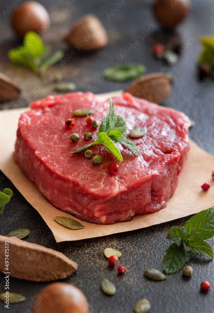 Raw beef fillet steak with herbs and spices on dark table close up