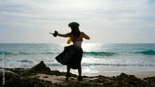 Woman rests and poses happily on the beach wearing the typical hula dance costume. Hawaiian dance beauty. Exotic girl. Silhouette of woman dancing hula. photo