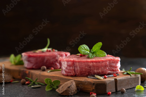 Raw beef fillet steaks with herbs and spices on dark table close up