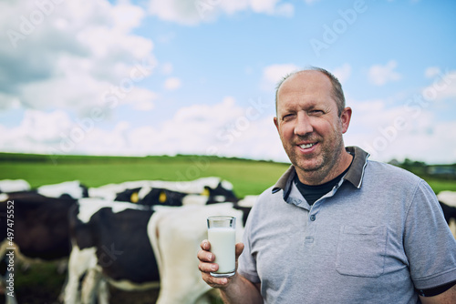 Its only the best on my farm. Cropped portrait of a male farmer standing with a glass of milk on his dairy farm.