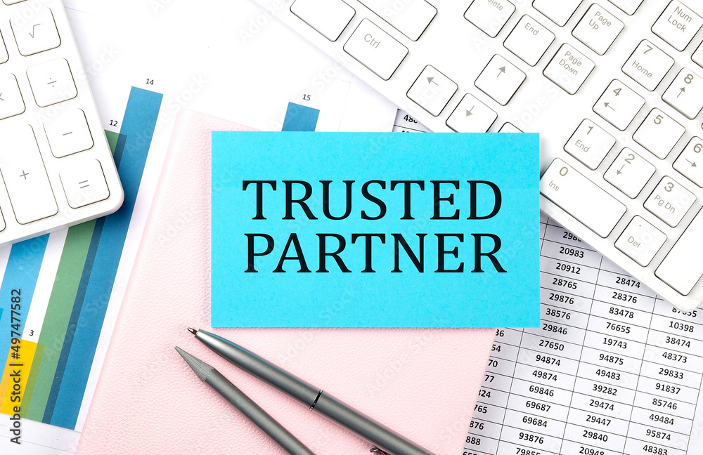 TRUSTED PARTNER text on blue sticker on chart with calculator and keyboard,Business concept TRUSTED PARTNER text on blue sticker on chart with calculator and keyboard,Business concept
