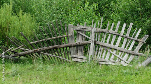 Collapsed village fence in summer on the grass