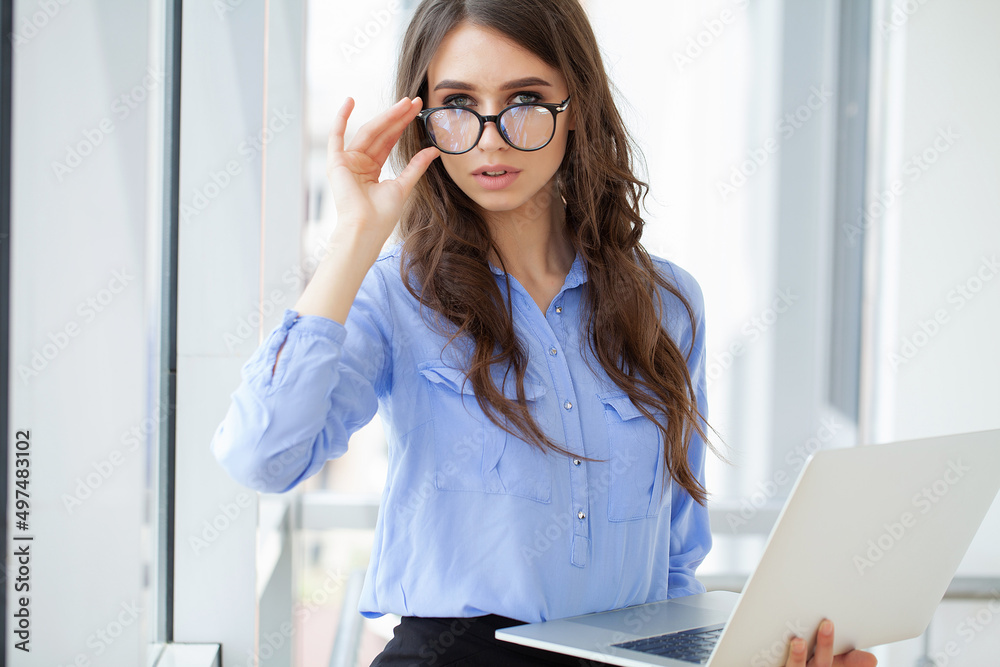 Beautiful business woman is using a laptop and smiling while working in office Beautiful business woman is using a laptop and smiling while working in office