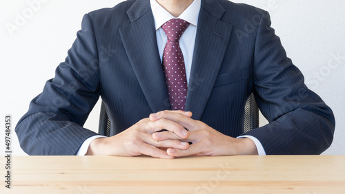 指を組んで座るビジネスマン｜威厳のある上司イメージ