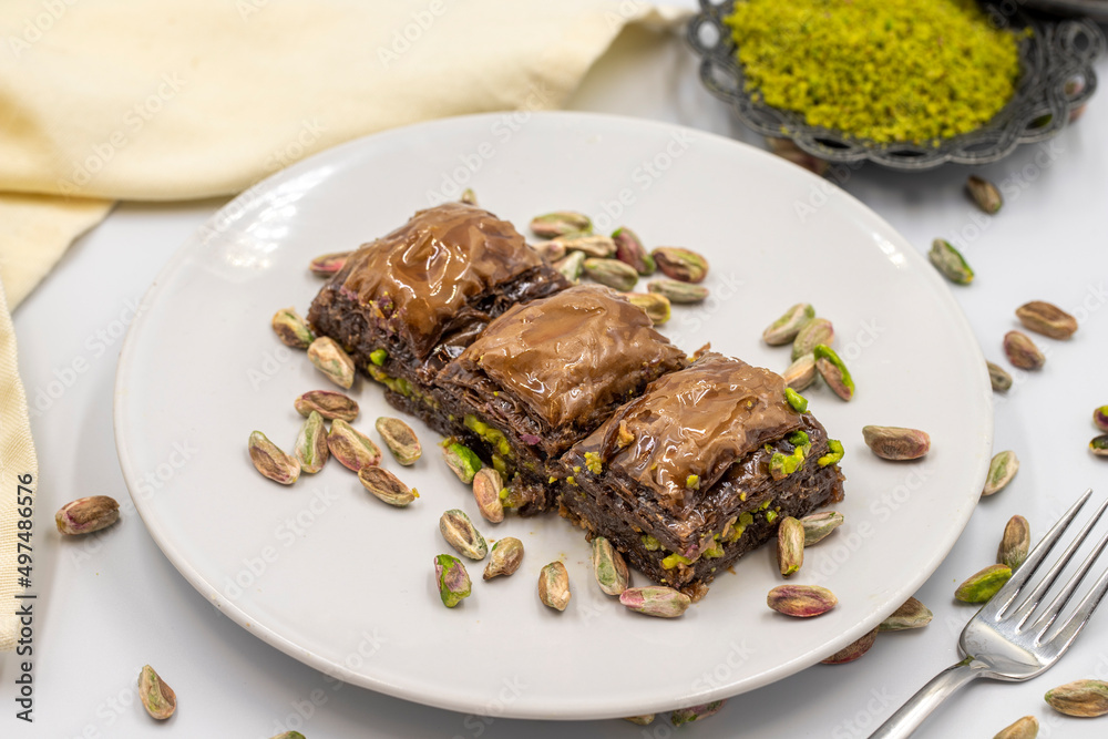 Chocolate baklava with pistachio on a white background. Traditional Mediterranean cuisine delicacies. Close-up Chocolate Baklava. local name cikolatali baklava Chocolate baklava with pistachio on a white background. Traditional Mediterranean cuisine delicacies. Close-up Chocolate Baklava. local name cikolatali baklava