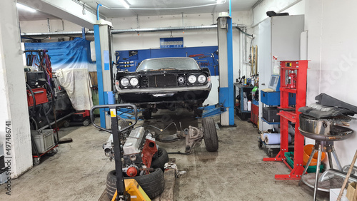 A vintage car is in a workshop being restored