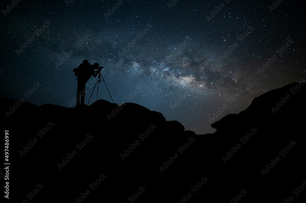 Milky Way.Night blue sky with stars and silhouette of a Backpack photographer  on the mountain. DEEP Space background.