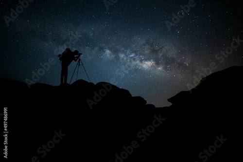 Milky Way.Night blue sky with stars and silhouette of a Backpack photographer on the mountain. DEEP Space background.