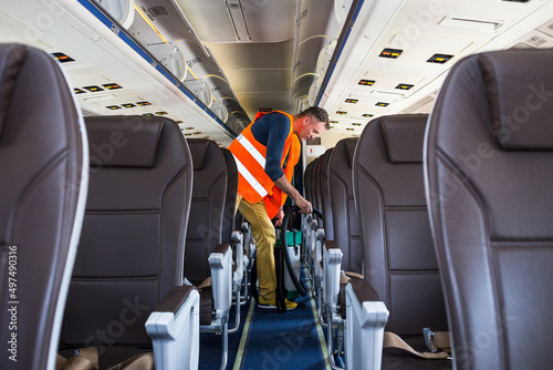 Aircraft cleaning service. Man cleaner working in airplane salon