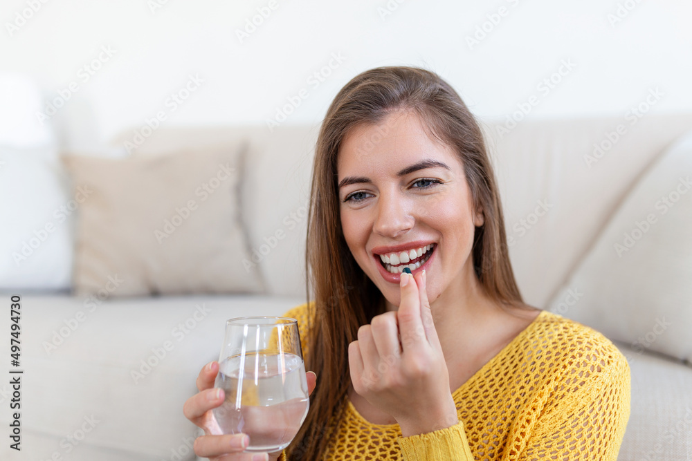Head shot smiling young woman holding pill and glass of fresh pure water. Healthy millennial lady taking antioxidant medicine vitamins, beauty supplements for hair skin nails, healthcare concept. Head shot smiling young woman holding pill and glass of fresh pure water. Healthy millennial lady taking antioxidant medicine vitamins, beauty supplements for hair skin nails, healthcare concept.