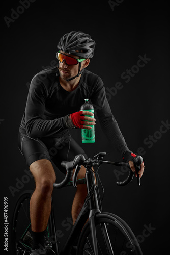 Fototapeta Naklejka Na Ścianę i Meble -  male cyclist riding road bicycle on black background