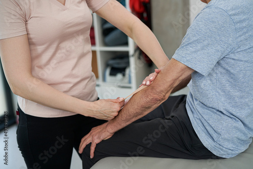 Physical therapist applying kinesio tape to the patient's hand