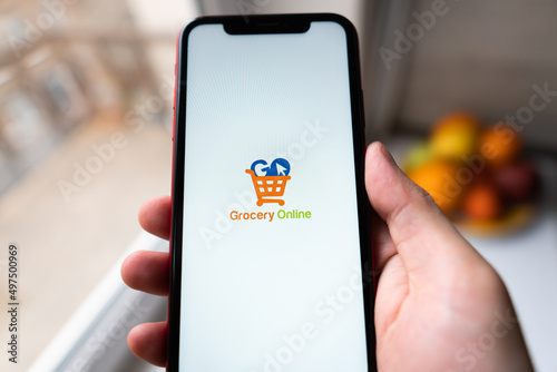 Smart phone with grocery shopping online on screen over blur kitchen background, retail business and technology concept