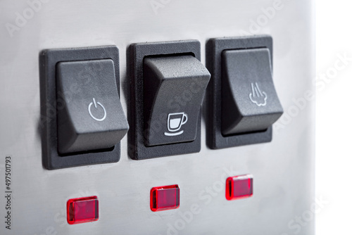 Black plastic buttons with turn on making coffee with a white cup icon of panel with buttons for professional espresso coffee machine of gray stainless steel, close-up details.