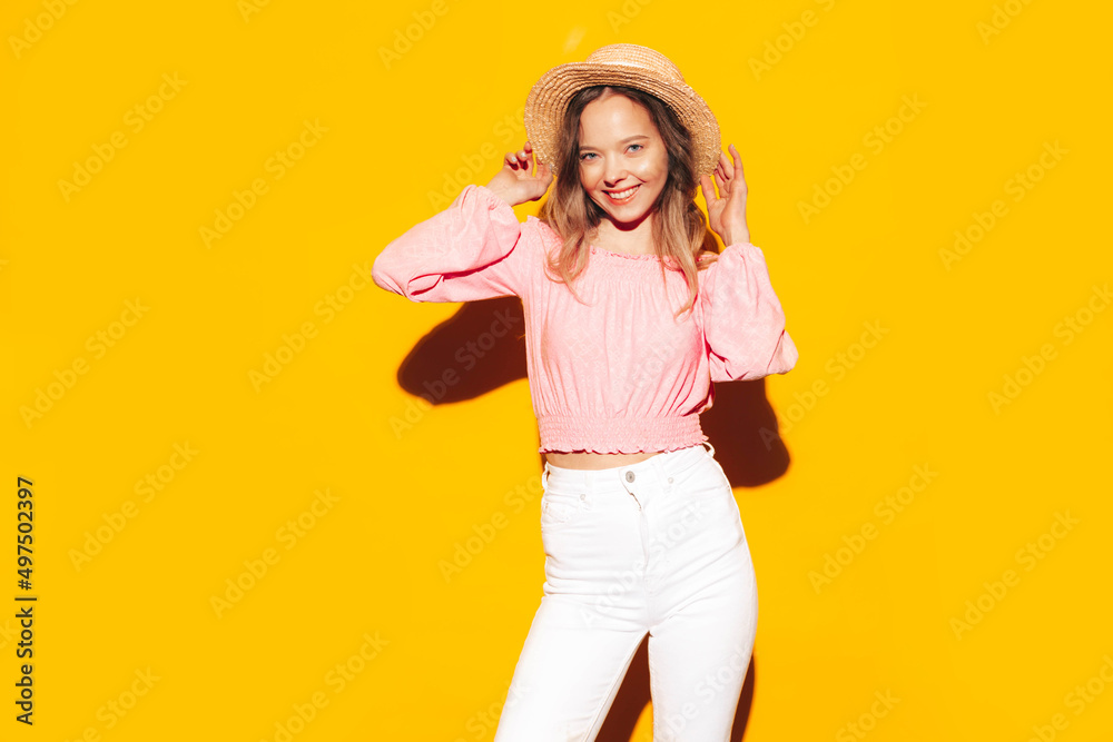 Portrait of young beautiful smiling blond female in trendy summer clothes. carefree woman posing near yellow wall in studio. Positive model having fun indoors. Cheerful and happy. In hat Portrait of young beautiful smiling blond female in trendy summer clothes. carefree woman posing near yellow wall in studio. Positive model having fun indoors. Cheerful and happy. In hat