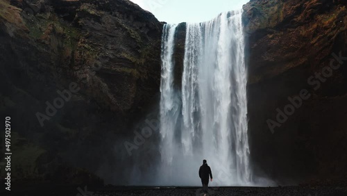 Man walking to Icelandic waterfall Skogafoss in Iceland, near the Skogar, slow-motion background wallpapers. Beautiful landscape. High quality 4k footage. Wide angle shot photo