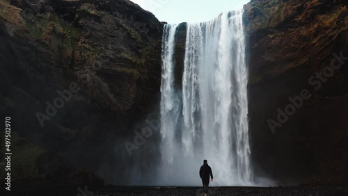 Man walking to Icelandic waterfall Skogafoss in Iceland, near the Skogar, slow-motion background wallpapers. Beautiful landscape. High quality 4k footage. Wide angle shot