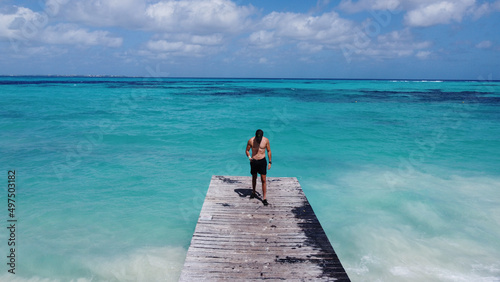 Man standing on wooden bridge and his back to the sea in Tulum Beach Mexico Caribe Cancun