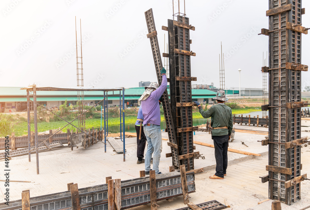 Construction workers installing formwork column pillar - obrazy, fototapety, plakaty 