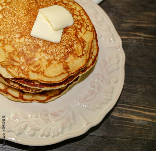 View of golden brown pancakes with two pats of butter on top. © Romar66