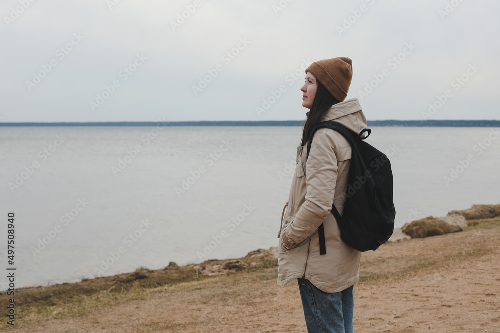 Portrait of young woman in a hat looking over the sea or the ocean, enjoying amazing nature, feeling of freedom