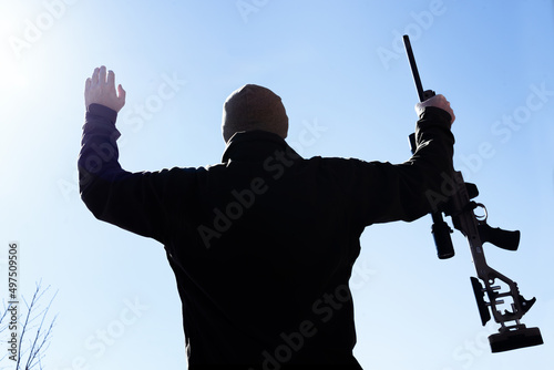 Capitulating soldier sniper rifles with an optical sight in man`s hands give up sunny day blue sky photo