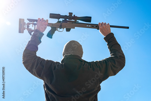 Capitulating soldier sniper rifles with an optical sight in man`s hands give up winter day blue sky photo