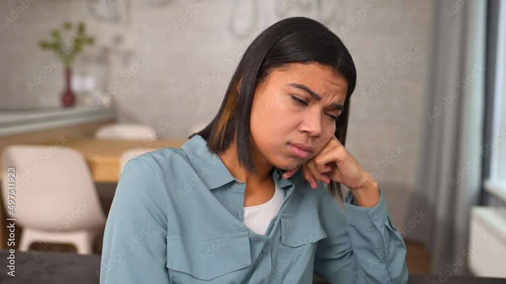 Upset African-American sitting on the sofa deep in thoughts and doubts, feels depression and sorrow, frustrated biracial female student failed exams worrying and nervous Upset African-American sitting on the sofa deep in thoughts and doubts, feels depression and sorrow, frustrated biracial female student failed exams worrying and nervous