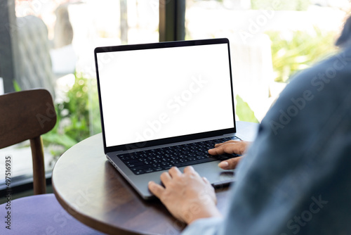 mock up empty screen notebook, businesswoman working on his laptop computer with blank space screen for advertising text on wood desk in Cafe