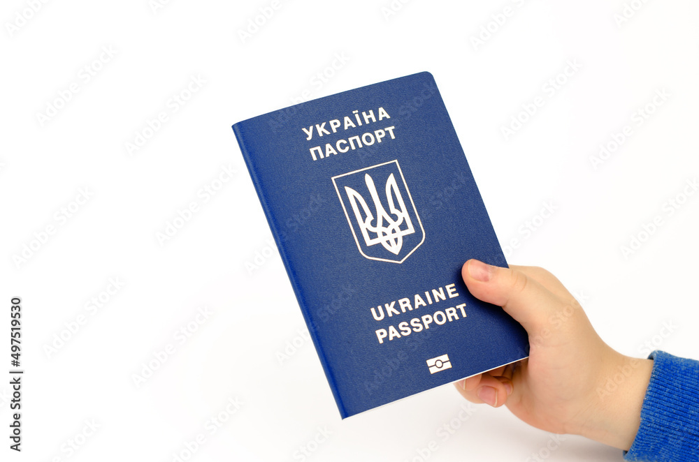 Biometric passport of a citizen of Ukraine in a child's hand on a white background. The inscription on the Ukrainian passport of Ukraine. Biometric passport of a citizen of Ukraine in a child's hand on a white background. The inscription on the Ukrainian passport of Ukraine.