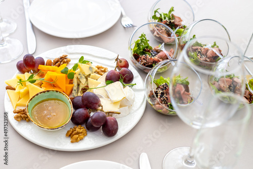 cheese plate with different types of cheese, grapes, honey and nuts.