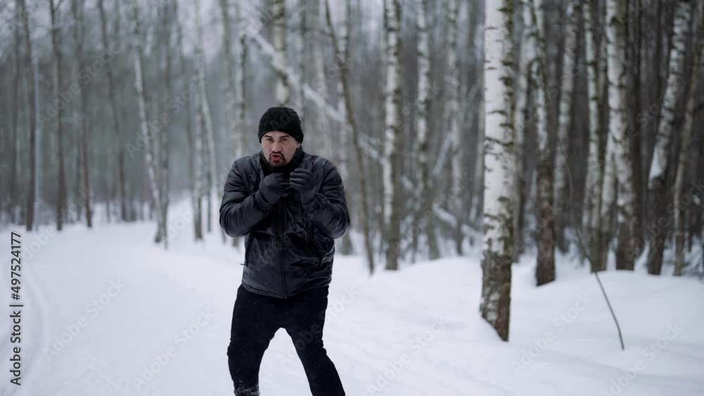 sporty man is training in forest in cold winter day, striking air by hands, practicing punches sporty man is training in forest in cold winter day, striking air by hands, practicing punches
