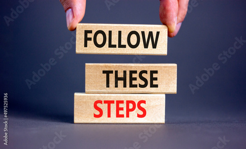Follow these steps symbol. Concept words Follow these steps on wooden blocks. Businessman hand. Beautiful grey table grey background. Business and follow these steps concept. Copy space. photo