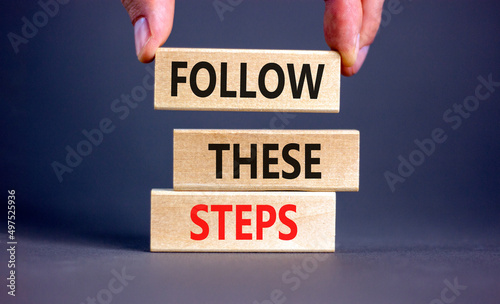 Follow these steps symbol. Concept words Follow these steps on wooden blocks. Businessman hand. Beautiful grey table grey background. Business and follow these steps concept. Copy space.