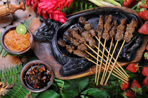 Various dishes - satay, sambal andaliman, salsa macha and red strawberries with artificial leaves photo