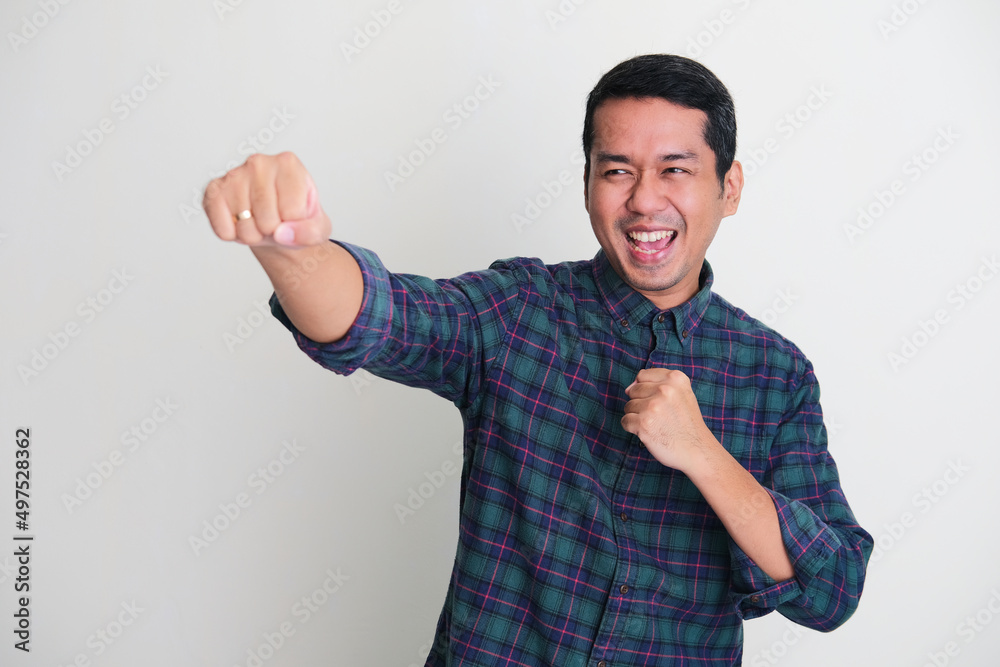 Fototapeta premium Adult Asian man punching forward with excited face expression