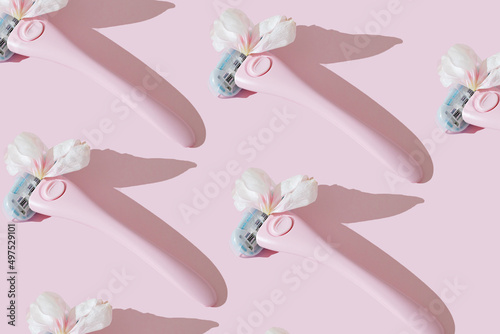 A pink women's razor shaving with white petals creative flat lay pattern. Beauty hygiene routine. Body positivity movement and gender inclusiveness idea. Pink background. Sensitive skin idea.