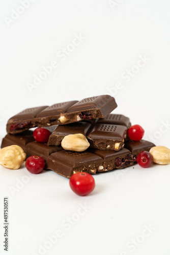 Stack of milk and dark chocolate with nuts, caramel and fruits and berries on a white background.