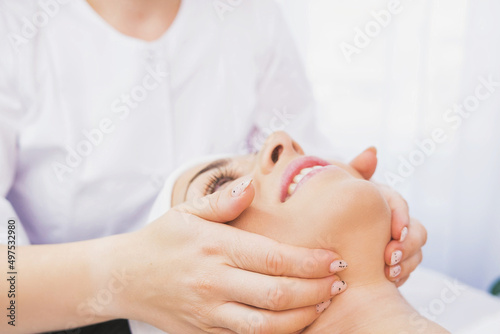 Cropped photo of beautician makes a facial massage procedure to a female face, client in a cosmetic clinic, facial skin care concept.